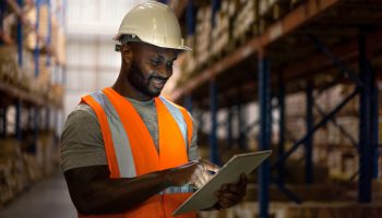 Warehouse worker using digital tablet to check inventory in storage room.