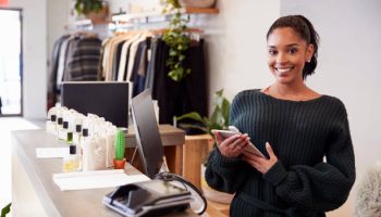 Female assistant smiling from the counter in clothing store
