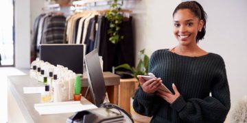 Female assistant smiling from the counter in clothing store